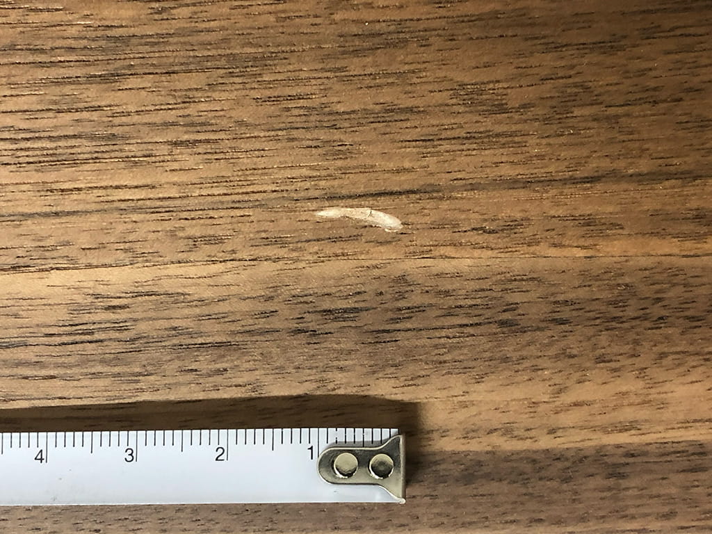 ものにぶつけてできた1cm程の傷がある木板の写真