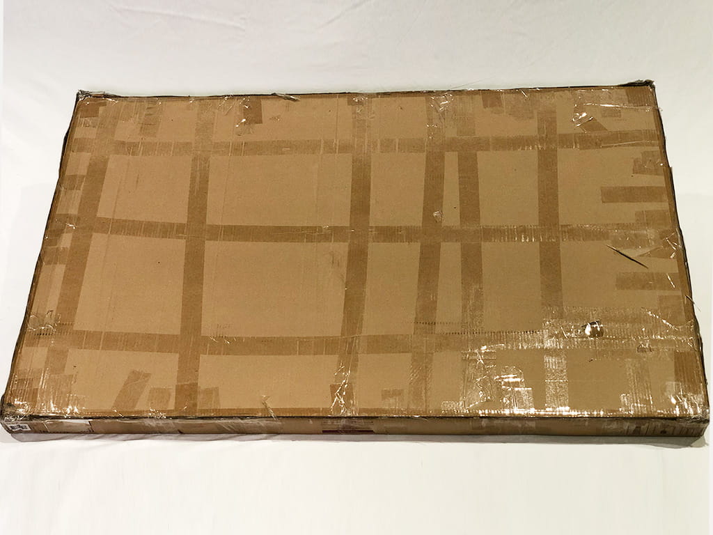 過剰にテープが貼られたくたびれたダンボールの梱包物の写真