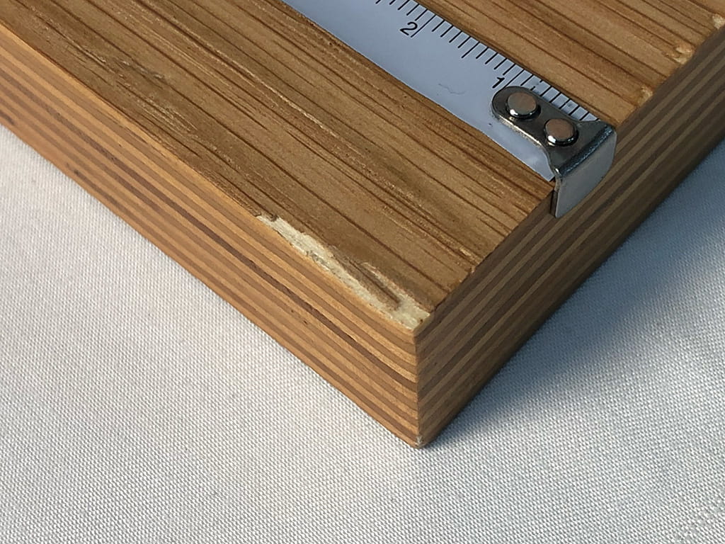 ささくれて角の隅のニスを塗った表面が剥がれてしまった木板の写真