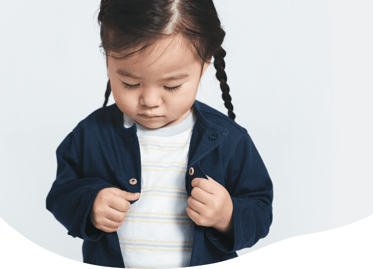 女の子がボタンをきちんとクルーネックカーディガンをひとりでお着替えするイメージ