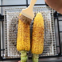 醤油を塗りながら焼かれているとうもろこしのイメージ画像
