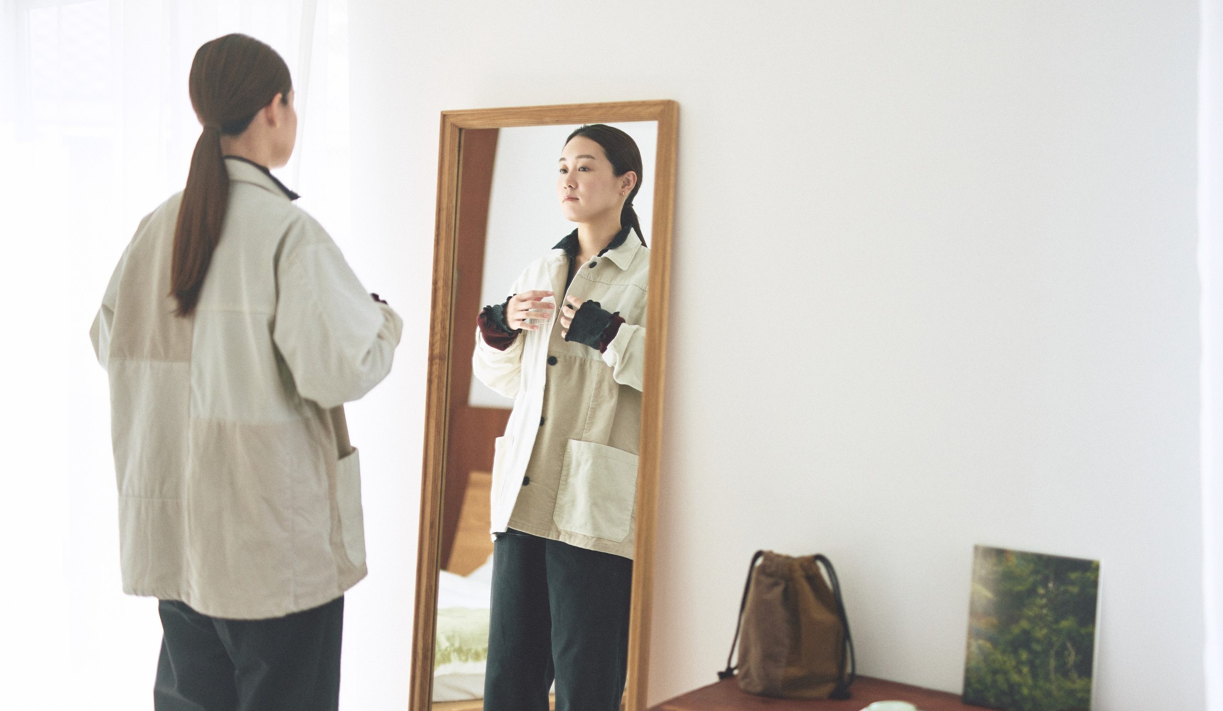 鏡の前で、つながる服のカバーオールを合わせるところ。