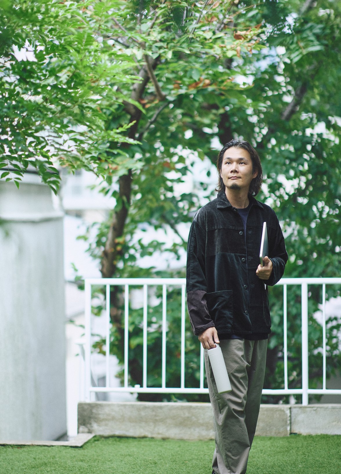 つながる服のジャケットを着て、木々の前に立つ姿。