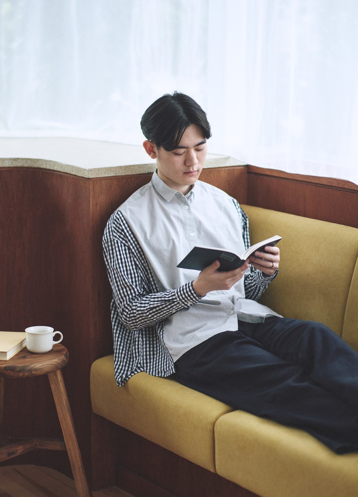 つながる服のシャツを着て、ソファで本を読むところ。