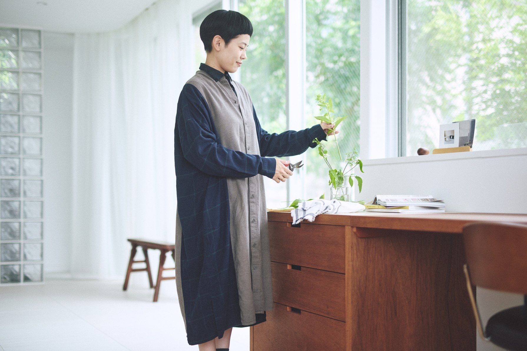 つながる服のロングシャツを着て、窓辺の植物に水をやるところ。