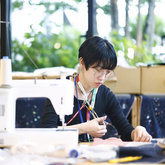 ミシンに向かうデザイナー。普段は無印良品の衣服や雑貨の企画開発を手がけています。