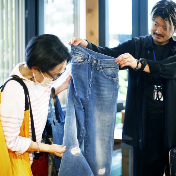 お持ち込みいただいたジーンズを広げ、仕上がりのイメージをお客さまと相談します。