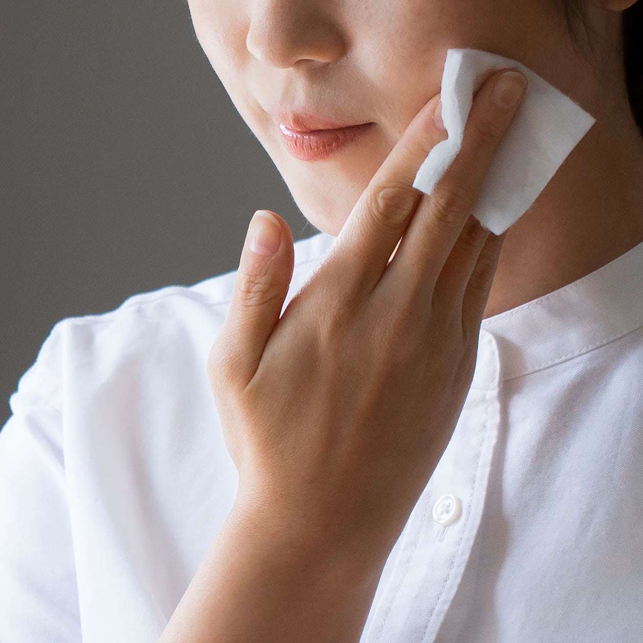 コットンをやさしく顔にすべらせていく女性