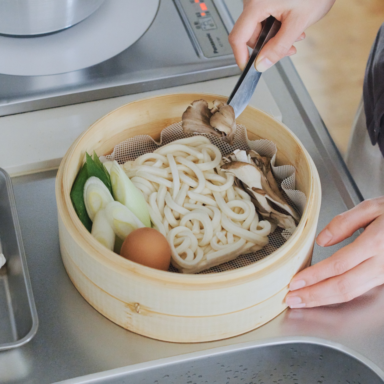 冷凍うどんと野菜、卵を蒸篭に並べているところ