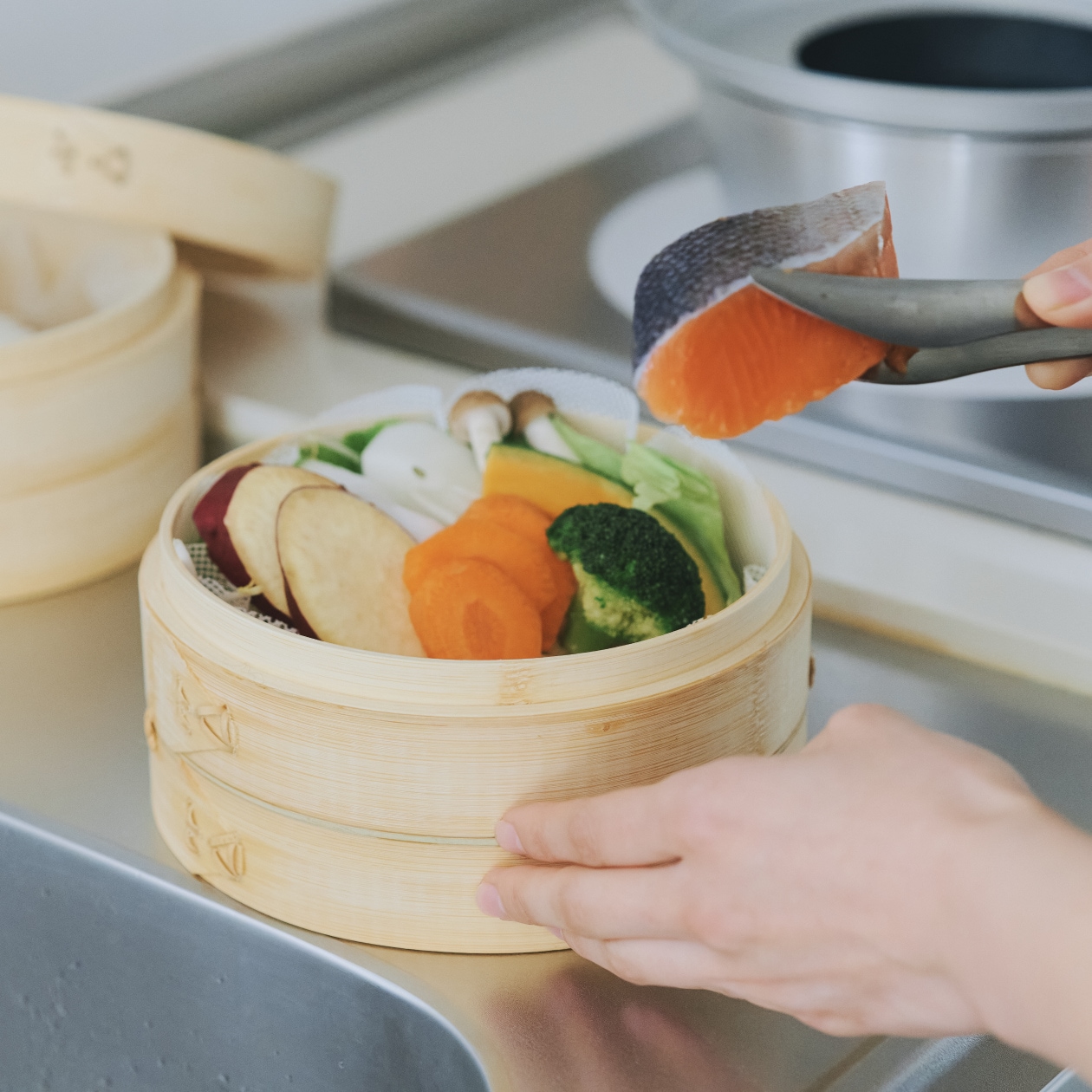 蒸篭で蒸しあがった鮭の切り身と野菜