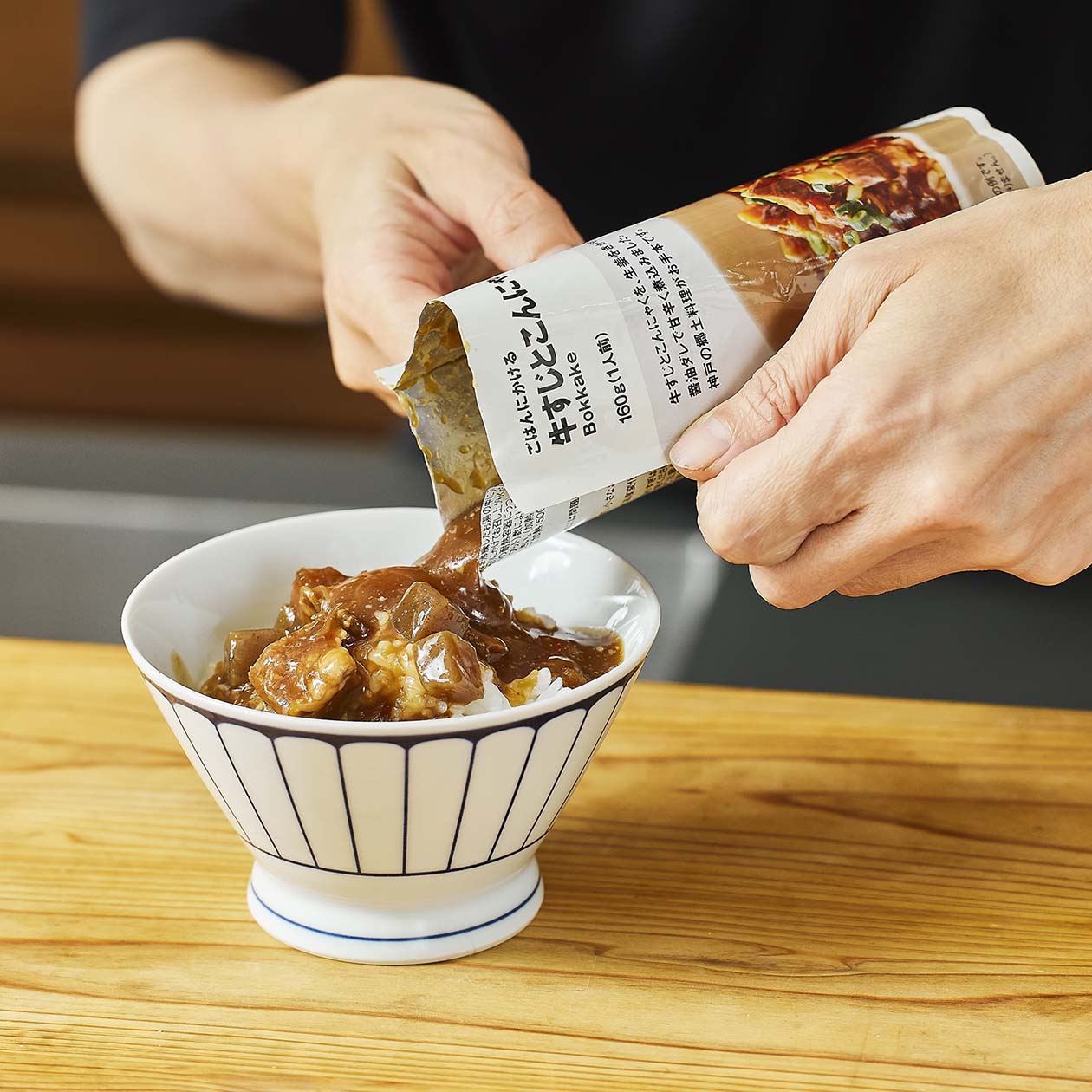 無印良品の牛すじとこんにゃくのぼっかけをごはんにかけているところ