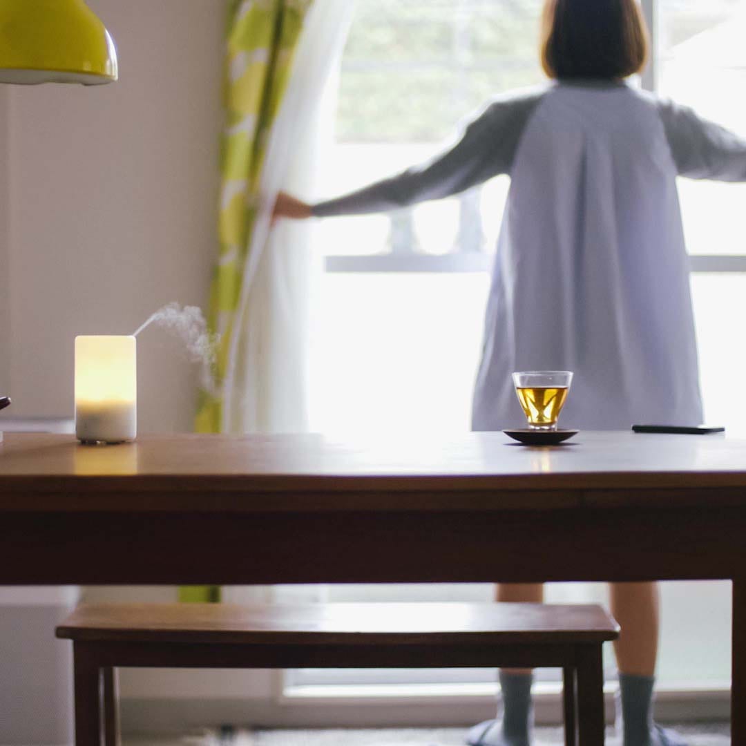 吐き出し窓を開けて換気をしようとしている女性