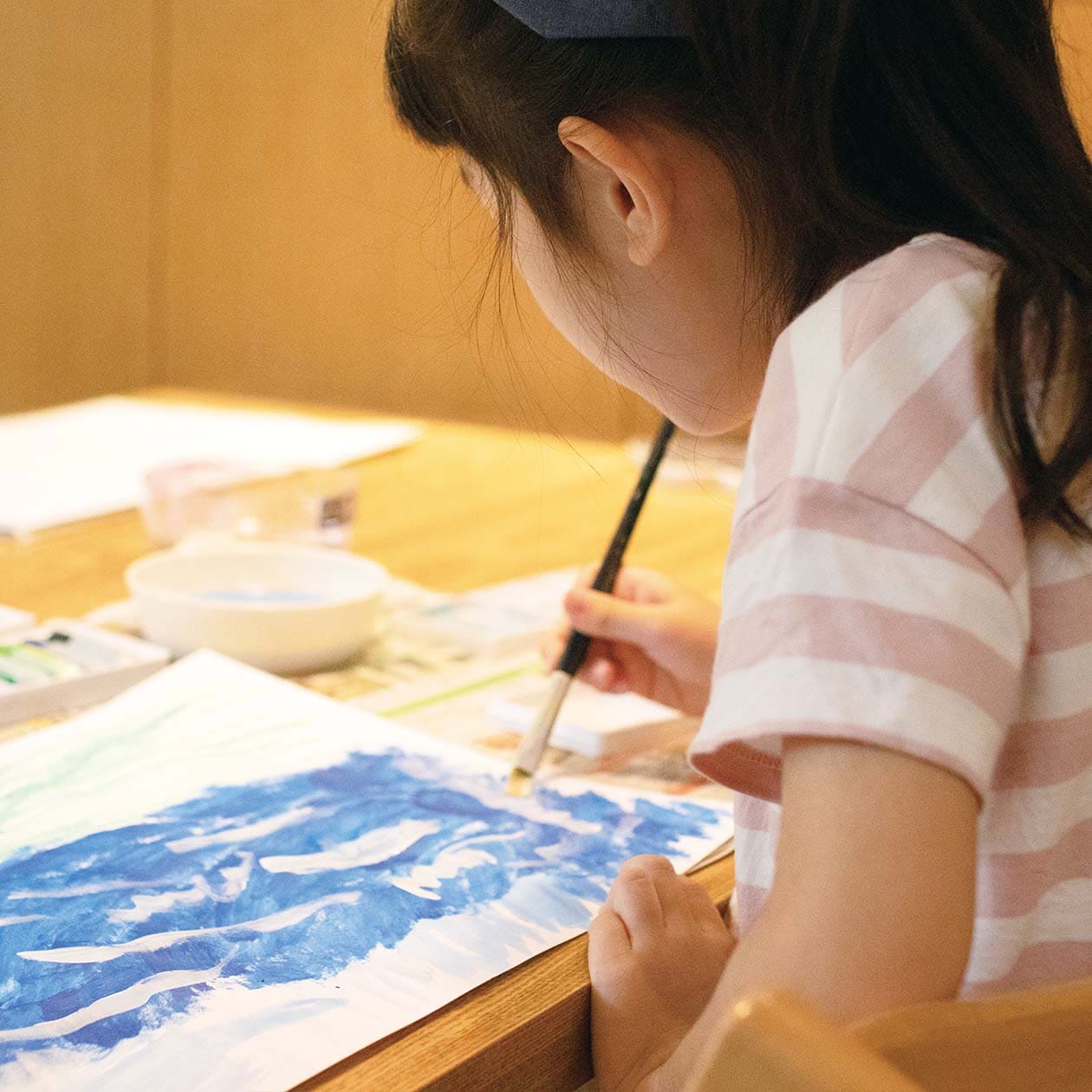 無印良品のTシャツを着て、水彩をかく女の子