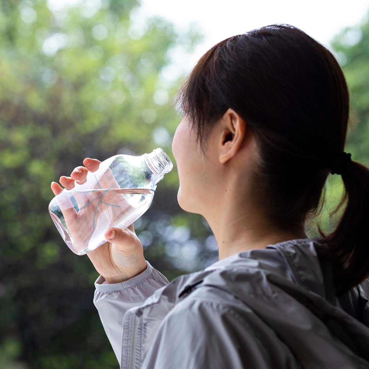 無印良品の水のボトルで水を飲もうとする女性