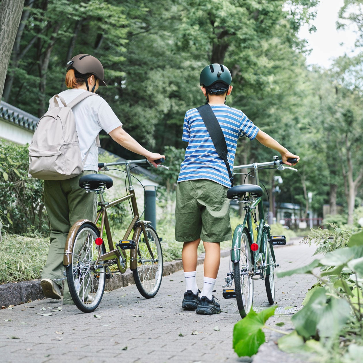 無印良品の風が抜ける自転車ヘルメットを着用し、20型自転車を押す親子