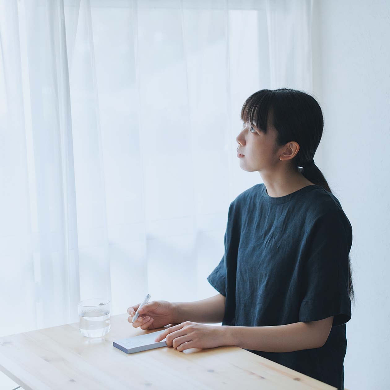 なにかをメモに記そうとしている女性