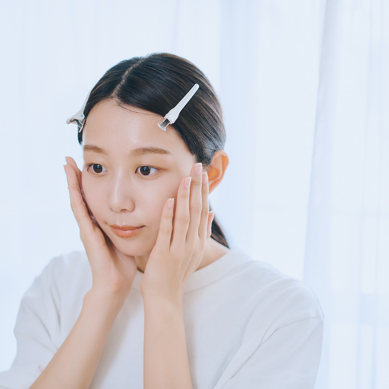 手のひらで頬に触れようとしている女性