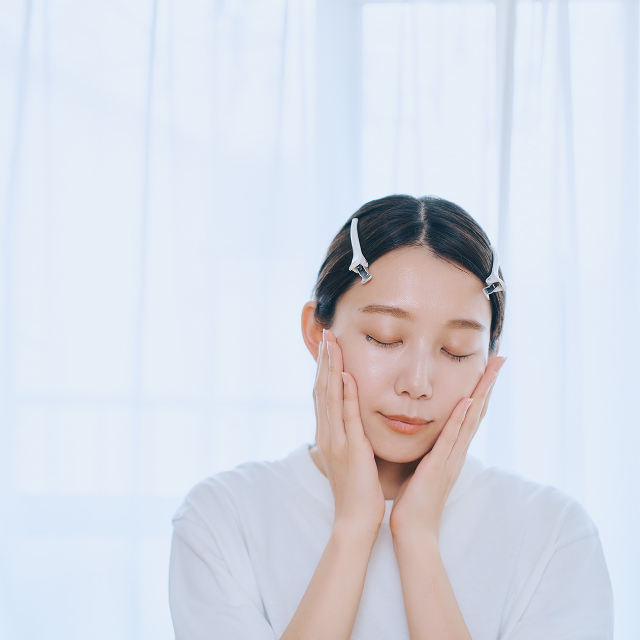 手のひらで頬に触れている女性