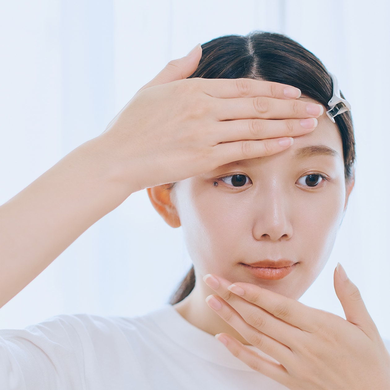 額と顎に触れている女性