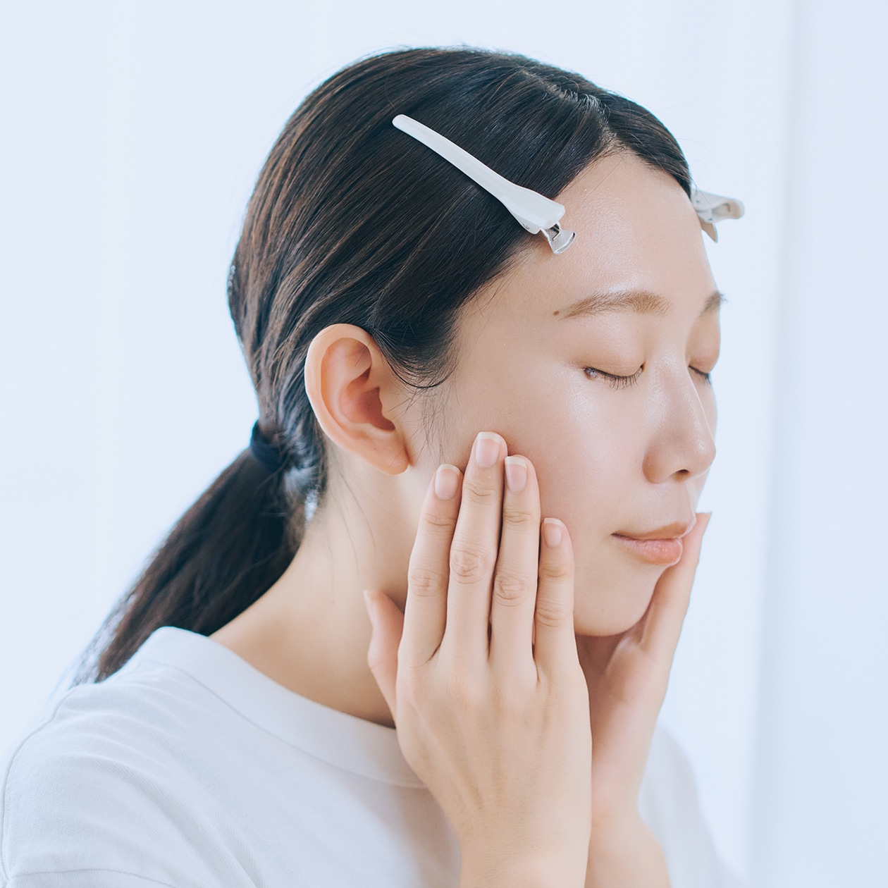 指で頬に触れている女性