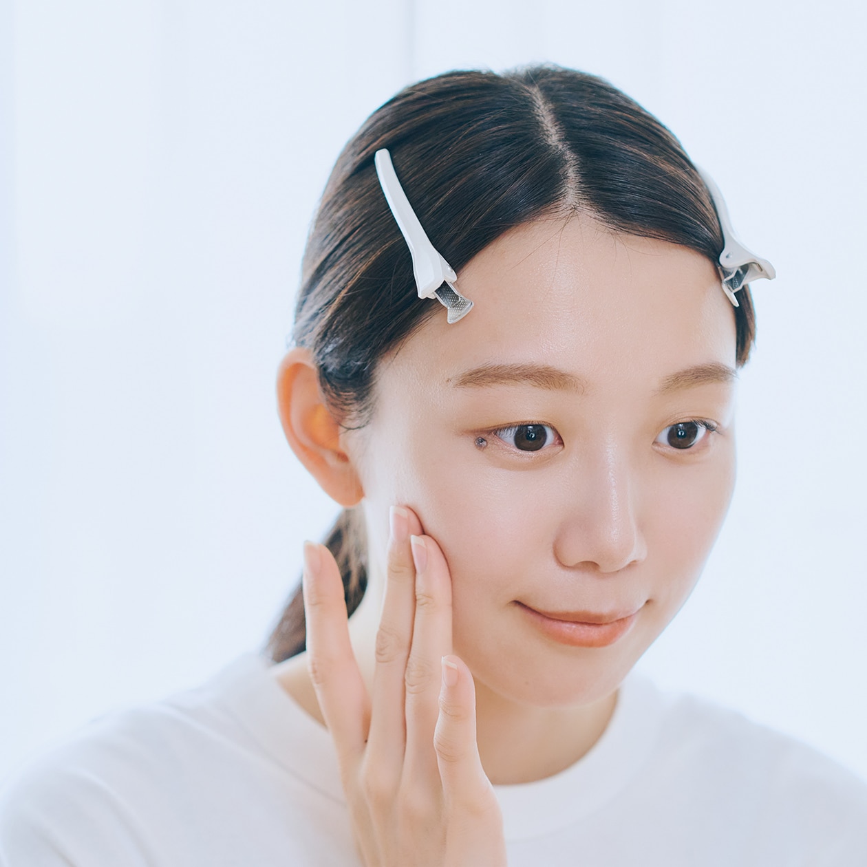 指で頬に触れている女性