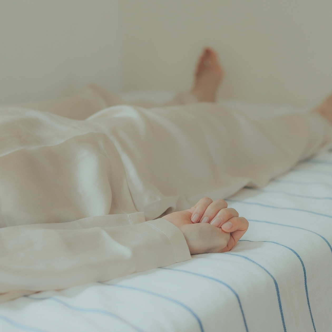 無印良品のパジャマをきて、手をぎゅっと握る女性の手元