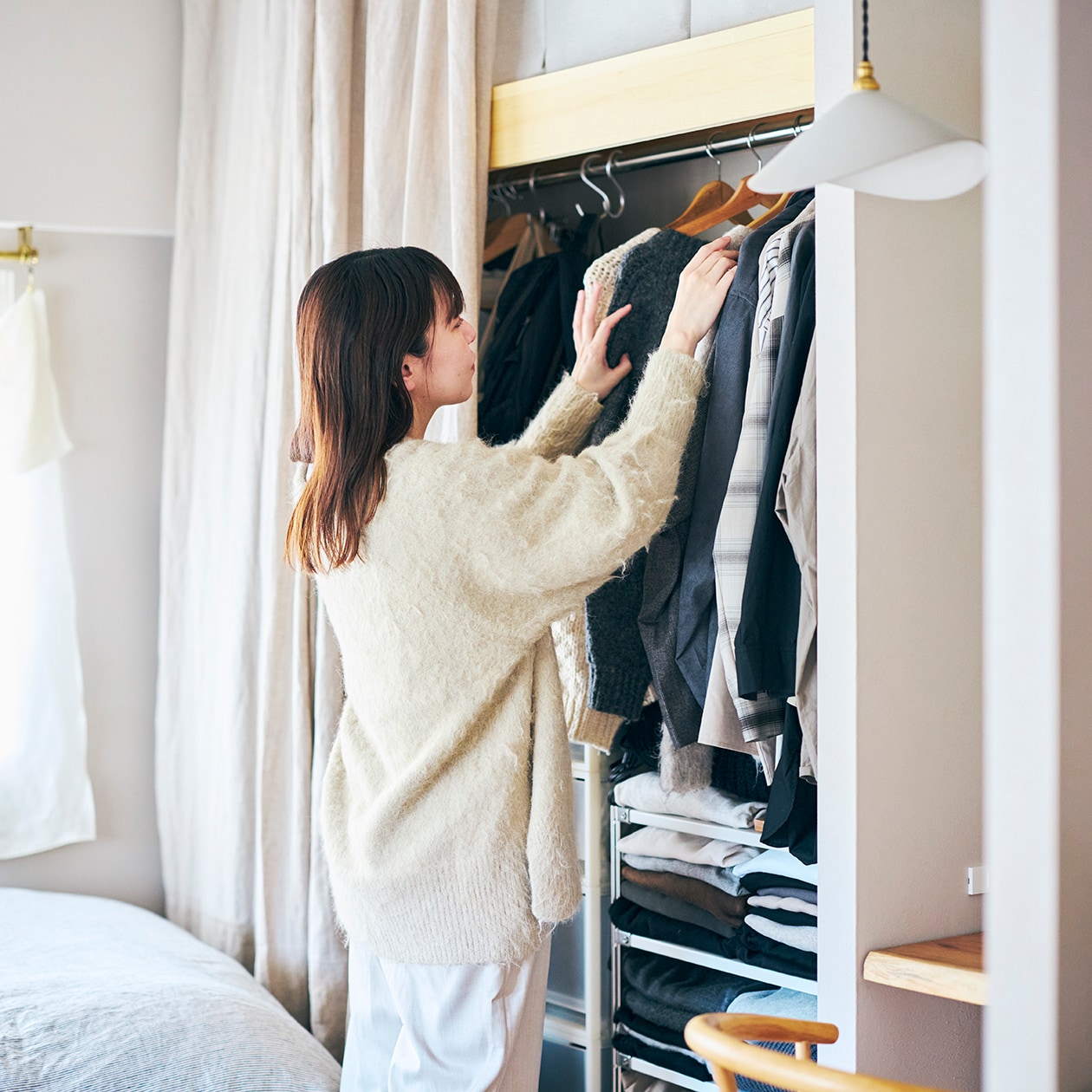 小さなクローゼットから服を探し出す女性