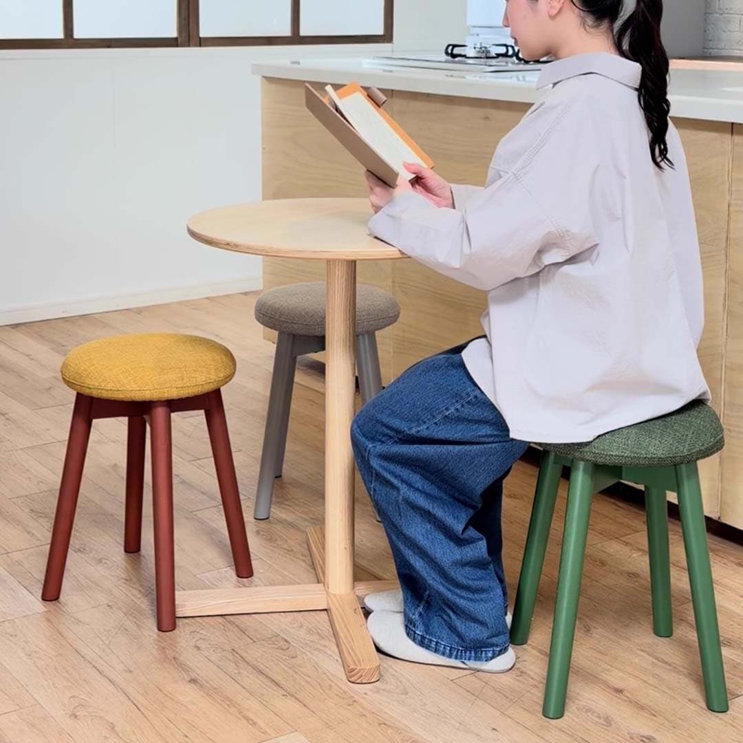 無印良品の 手軽に組み立てられる木製カフェテーブル と スツール で過ごす人物