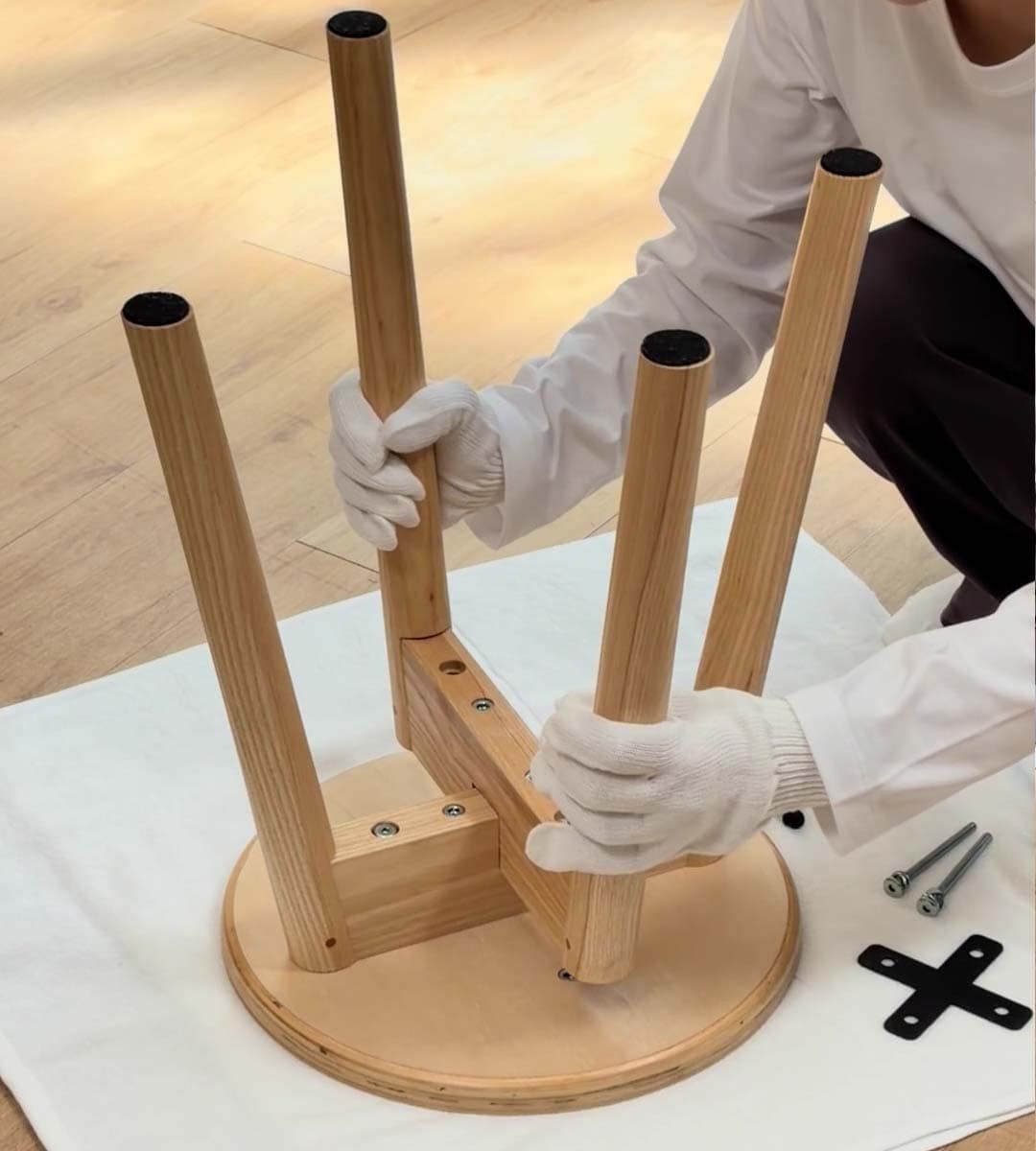 無印良品の木製スツールを組み立てる人物
