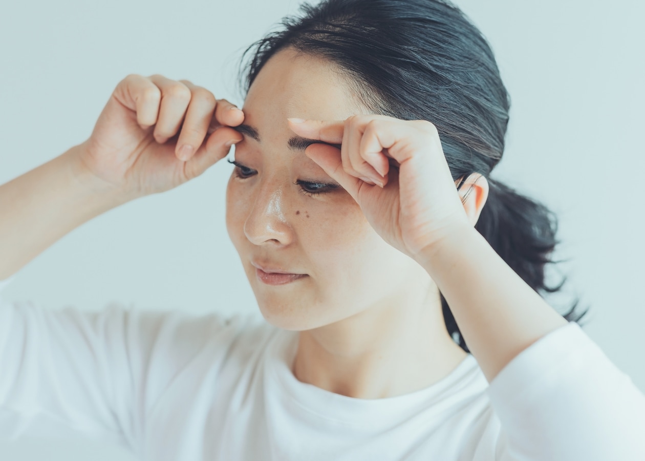 眉毛をもみほぐす女性