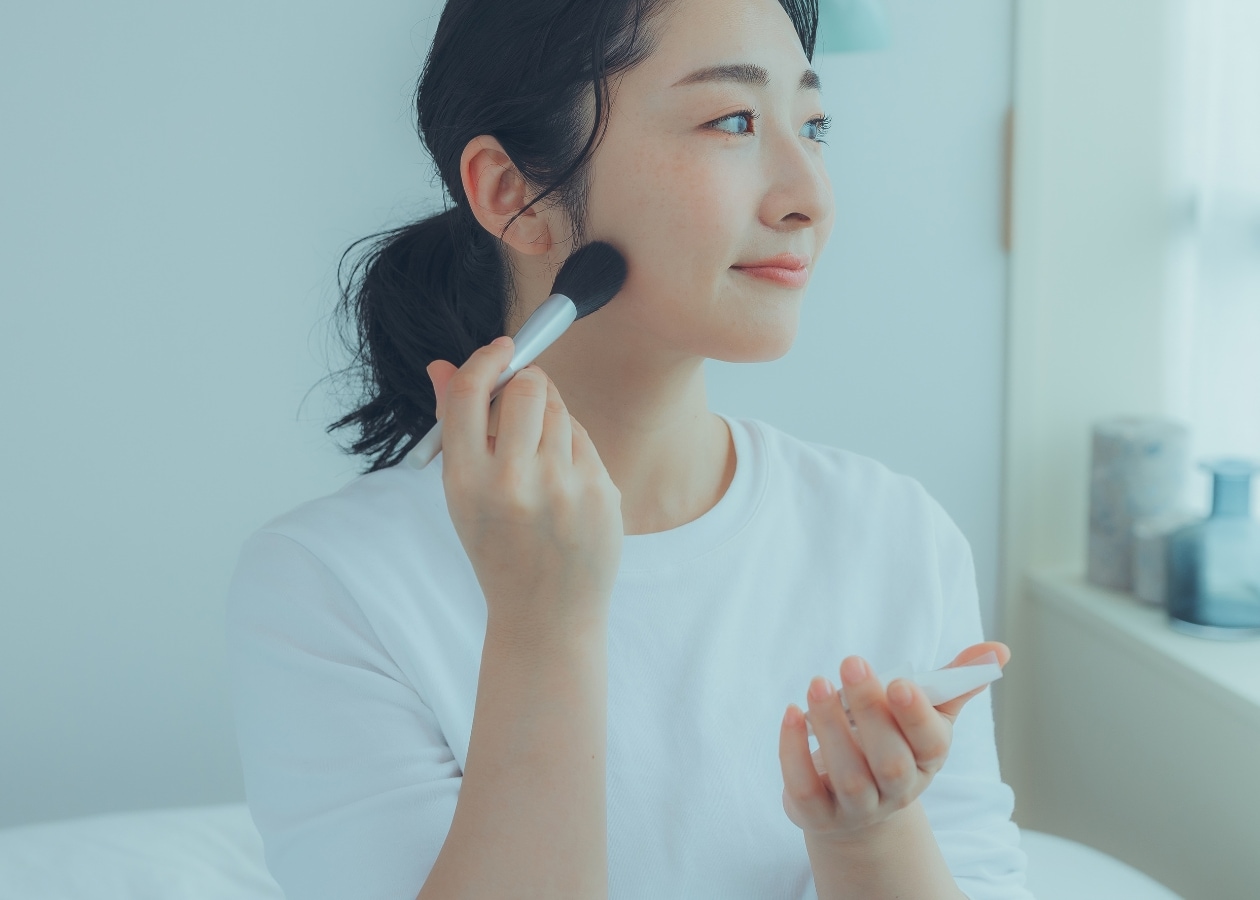 無印良品の肌あたりやわらかチークブラシでメイクをする女性