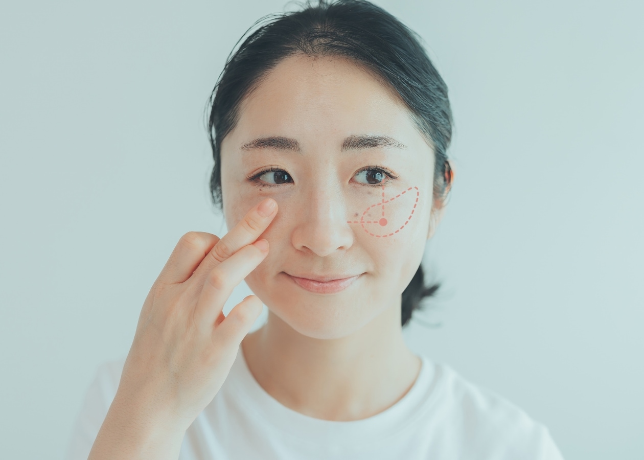 クリームチークを顔にのせる女性