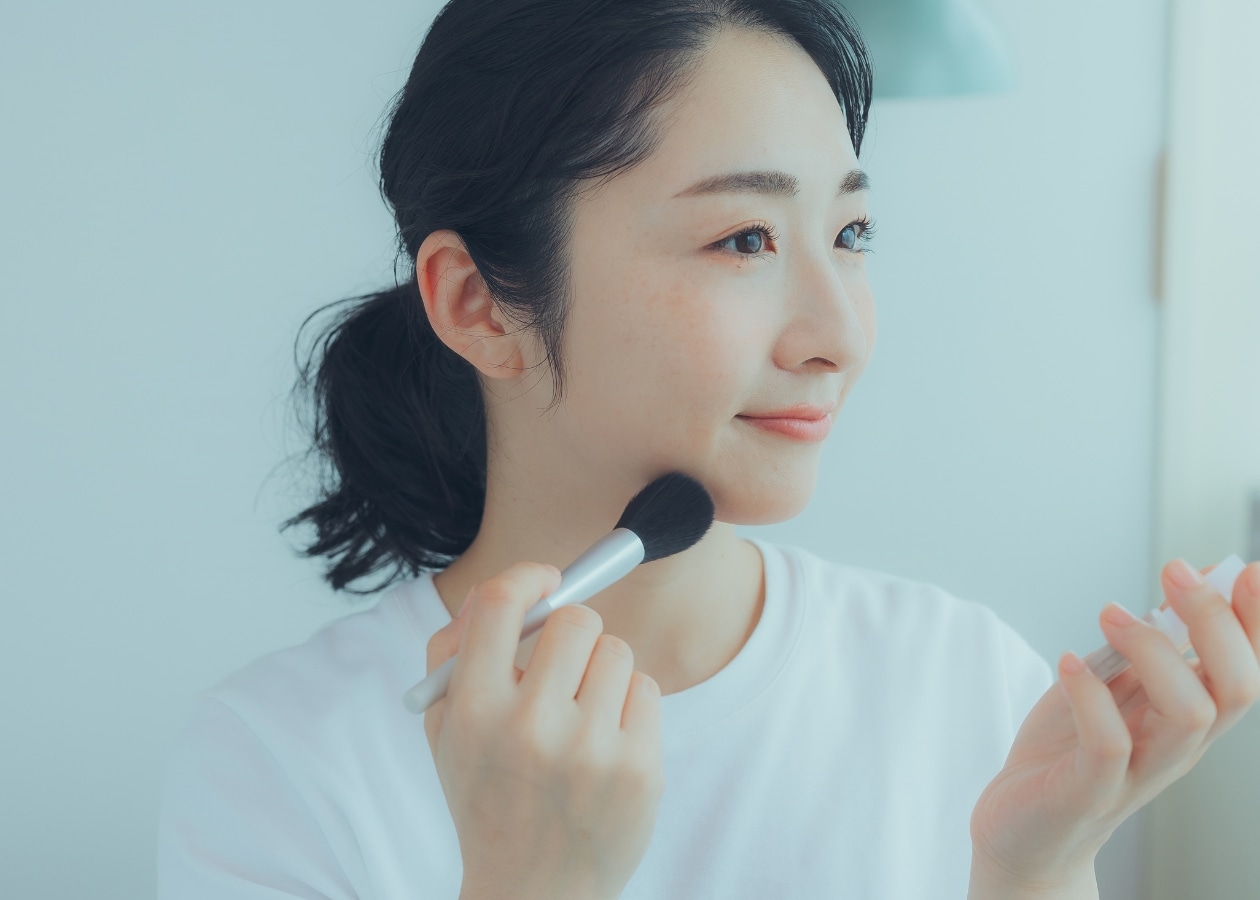 パウダーチークを重ねる女性