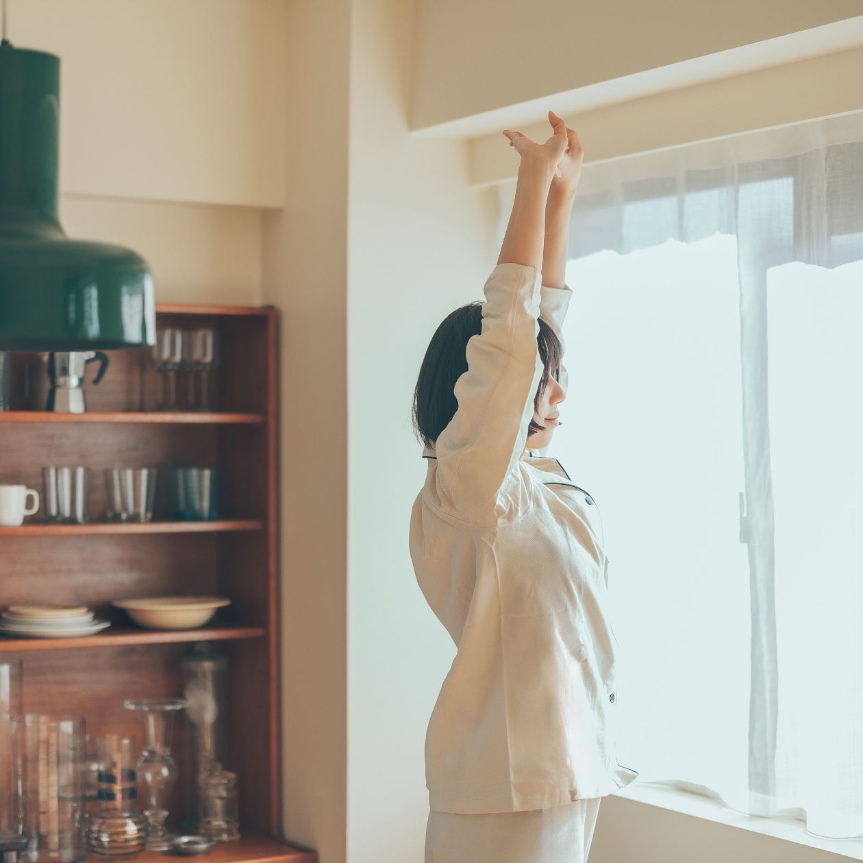 朝日を浴びながら伸びをする女性