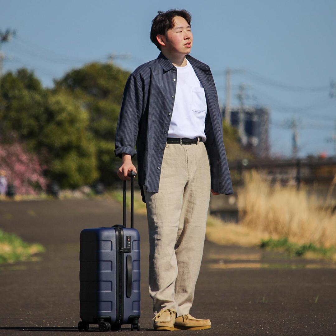 ヘンプシャツを半袖の上に羽織ってキャリーケースを持っている写真です