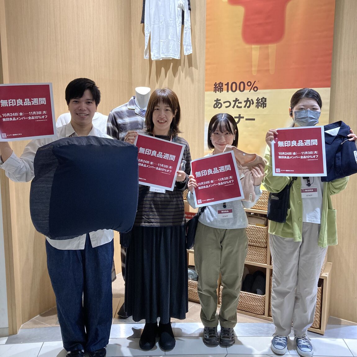 スタッフ4人で各自のお勧め商品を持ち、無印良品週間の告知をしている様子