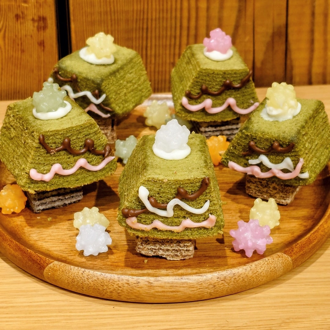 【テラスモール湘南】商品の宇治抹茶バウム、ひとくちウエハース、こんぺいとうをチョコでくっつけてクリスマスツリーに見立てたもの5個を、木のお皿に乗せて飾った写真