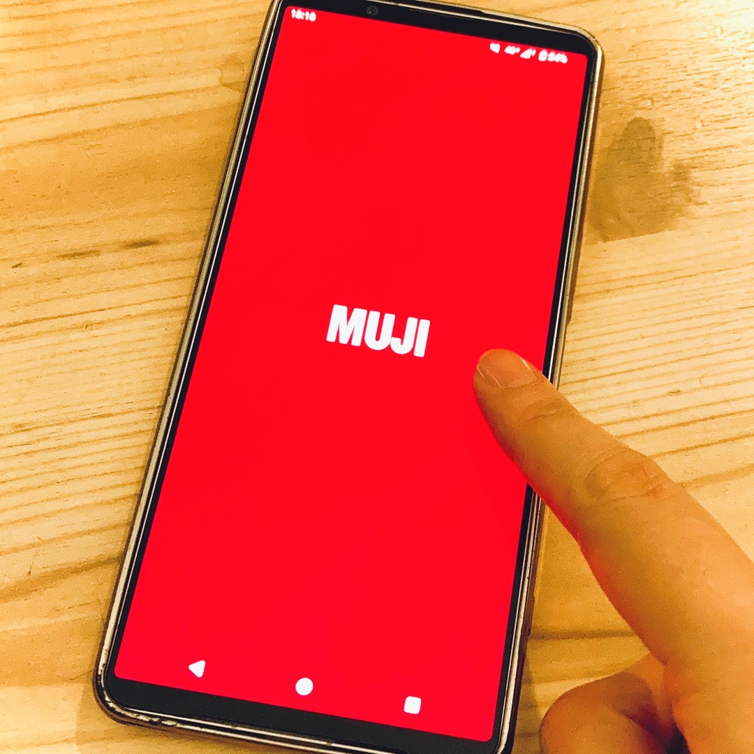【テラスモール湘南】MUJIアプリを起動中のスマートフォン画面を指でタップしている写真