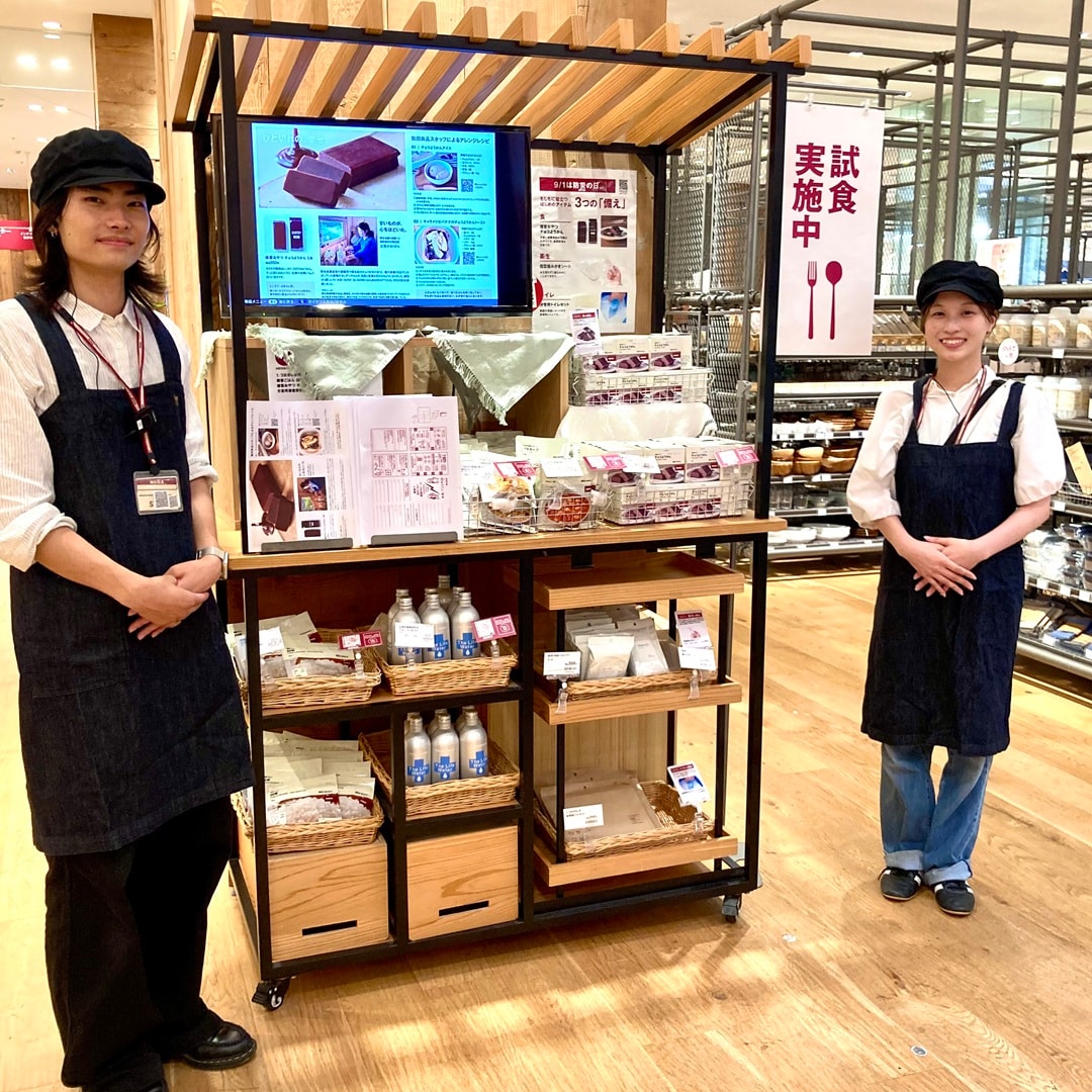 【テラスモール湘南】試食用のワゴンと「試食実施中」と書かれたのぼりを挟んで当店の男女スタッフが立ち、カメラに向かって微笑んでいる写真