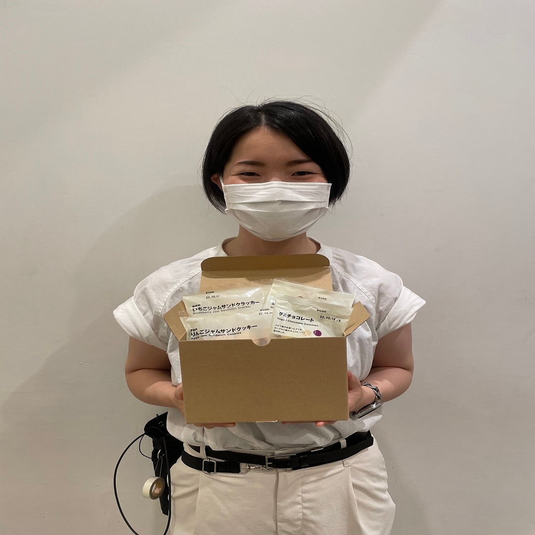 お菓子の入った箱を持つスタッフの写真