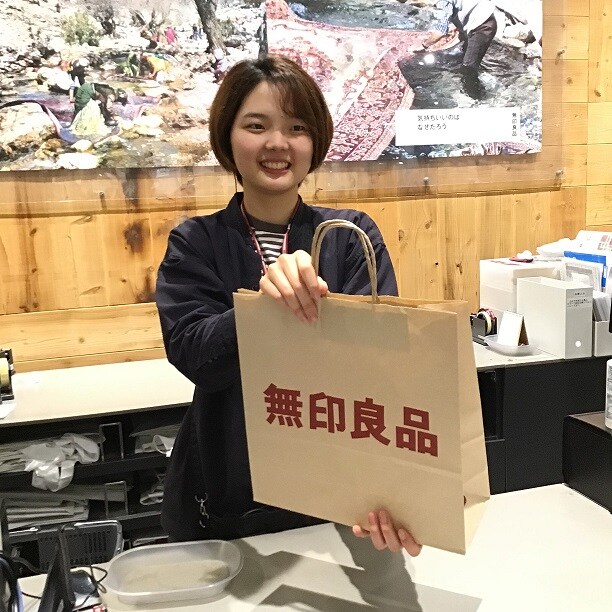 レジで紙袋を渡すスタッフの