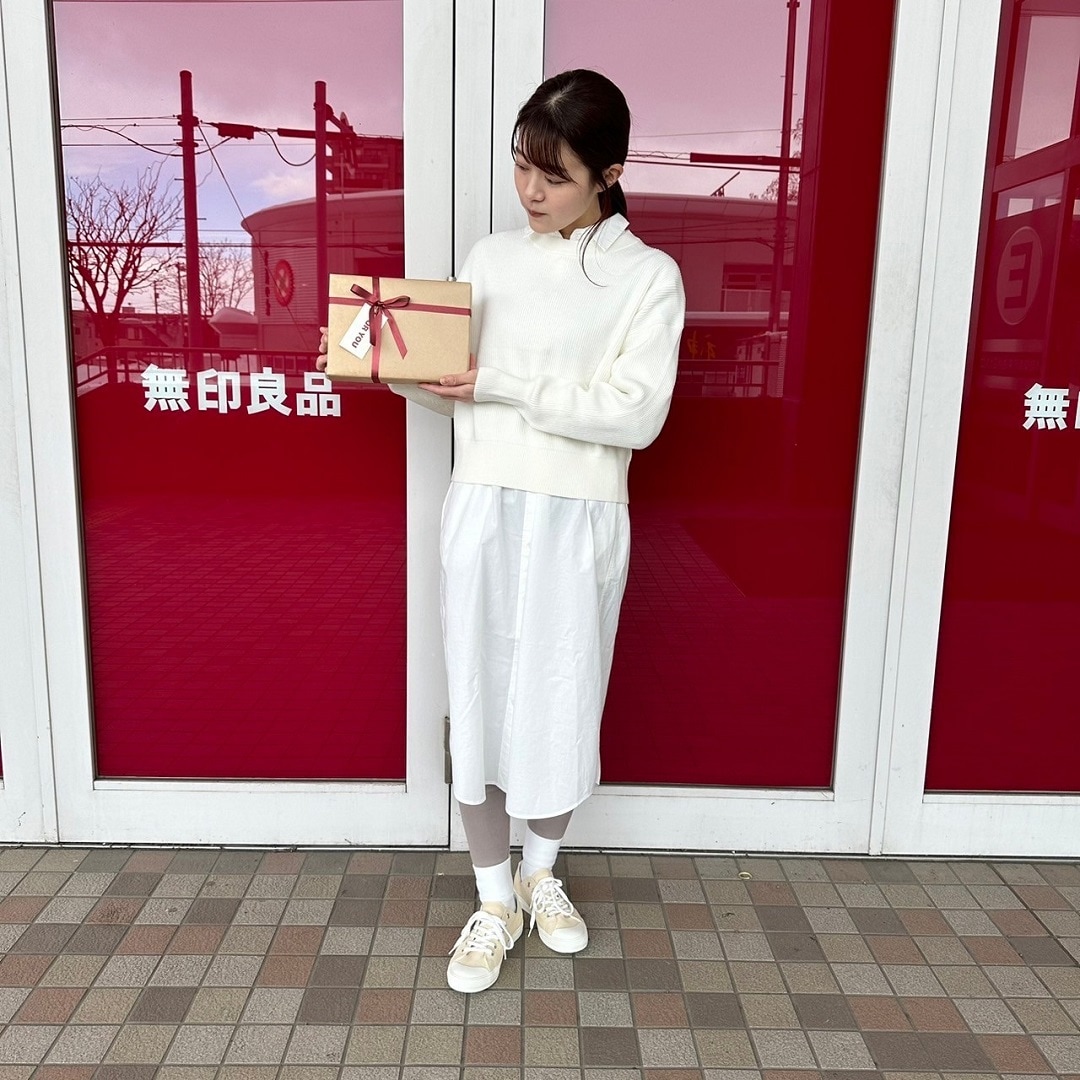 ギフトボックスを持ってクルーネックセーターを着た女性スタッフ