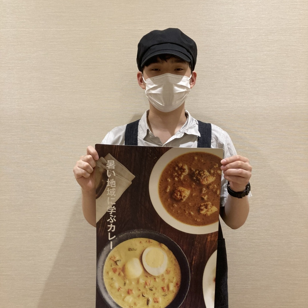 カレーのツールを持った試食担当者の写真