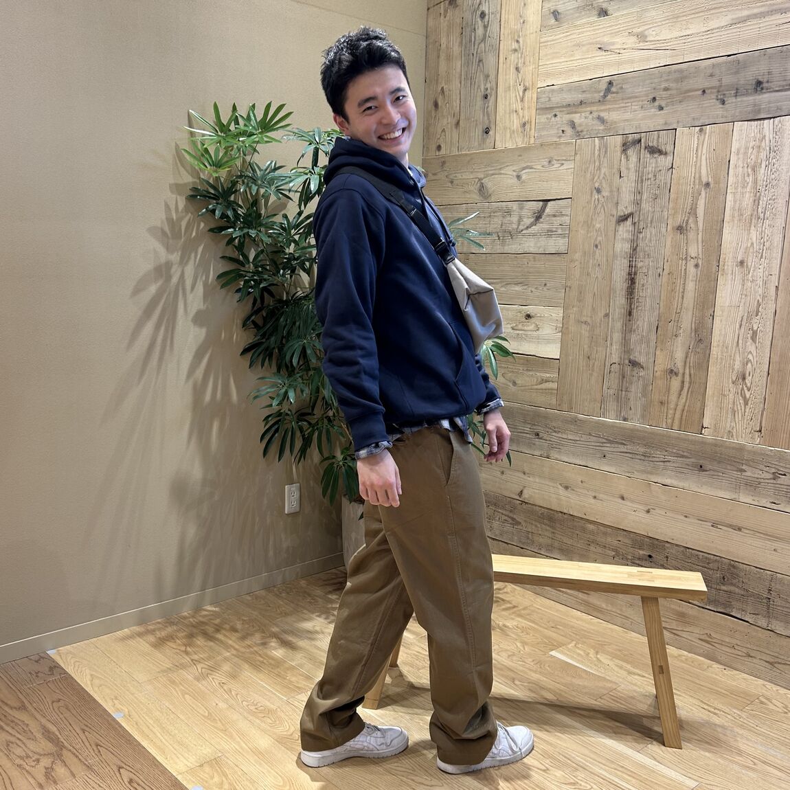 ネイビーのトレーナーにブラウンのパンツをはいて振り向く男性