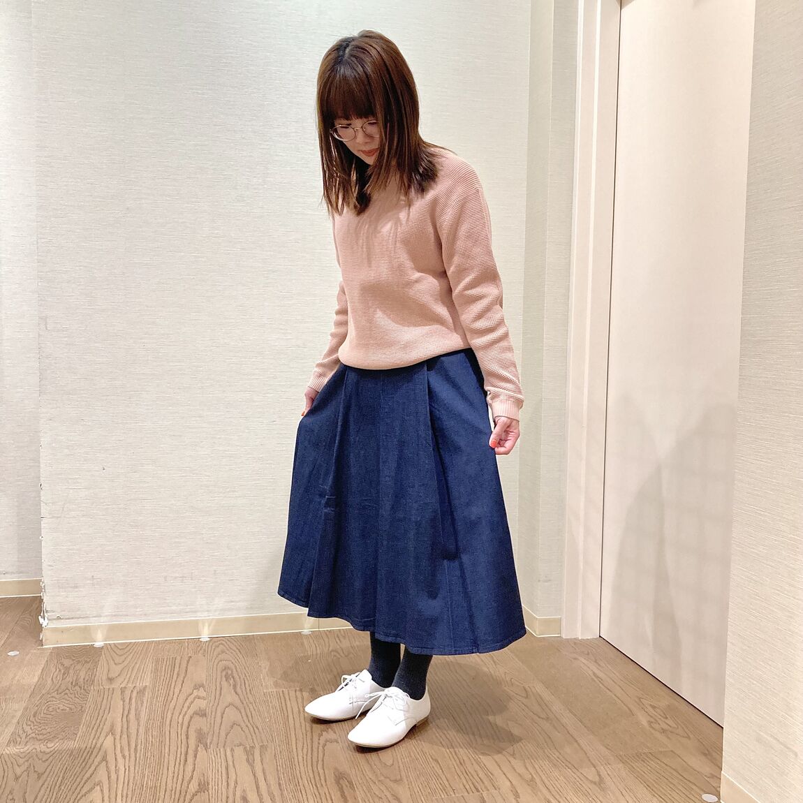 ピンクのセーターとダークネイビーのスカートを着用した女性