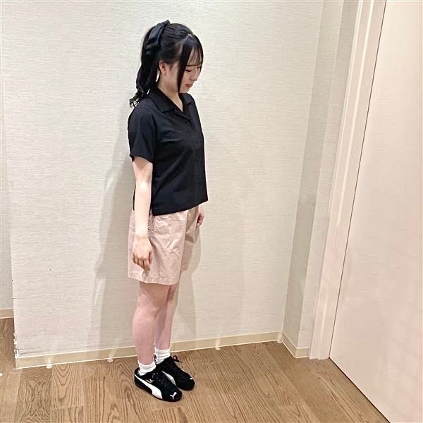 黒いオープンカラーシャツとピンクのショートパンツを着用した女性