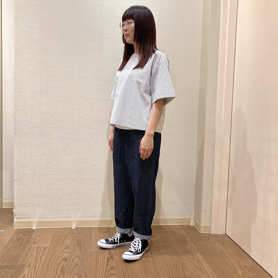 ストライプのブラウスにデニムのイージーパンツを着用した女性