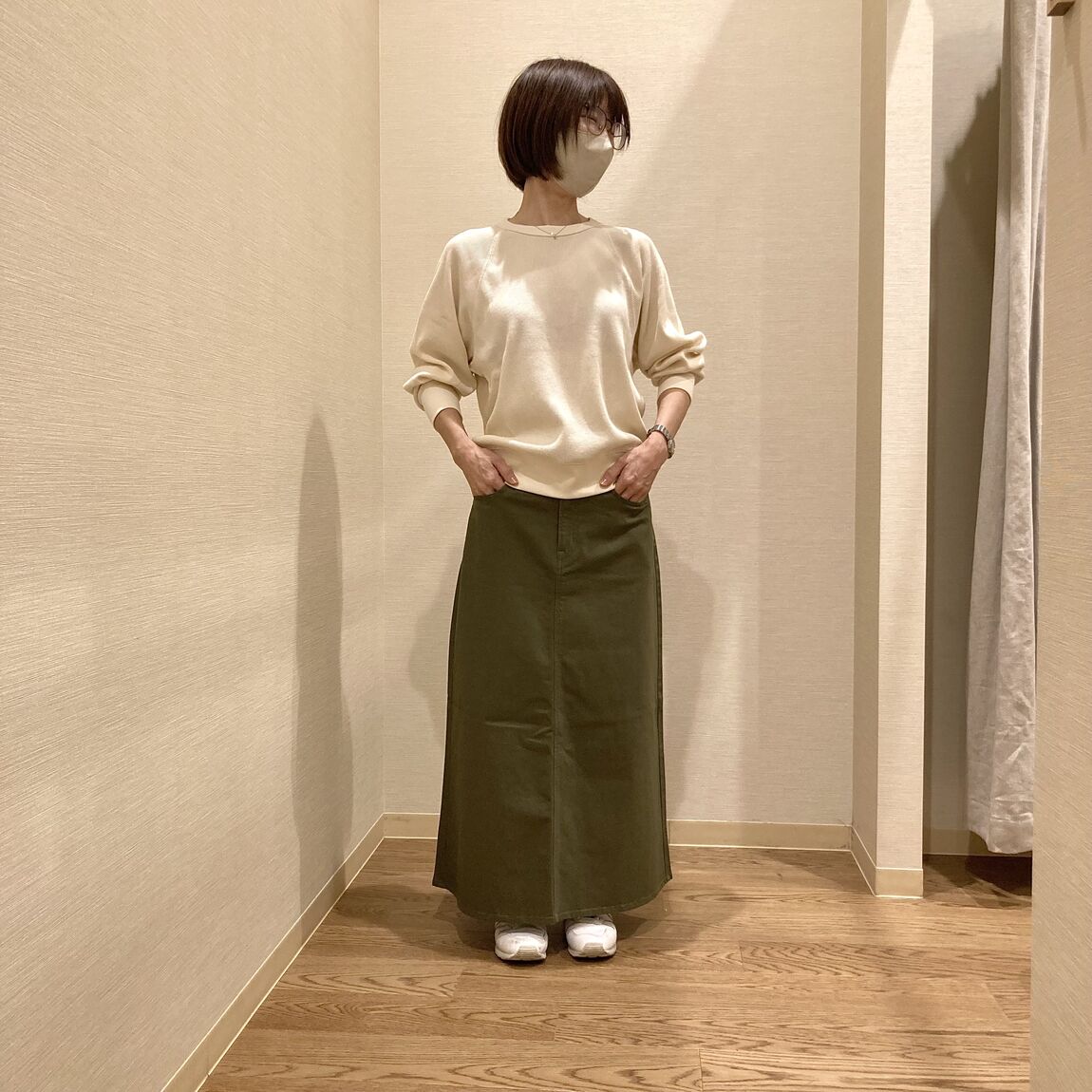 アイボリーのワッフルＴシャツとカーキのスカートを着用した女性