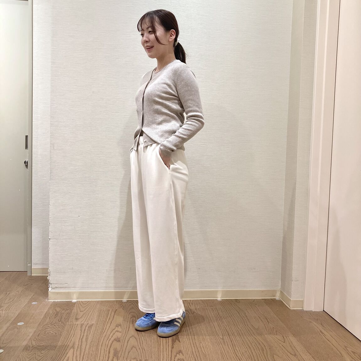 ベージュのカーディガンと白いスウェットパンツを着用した女性