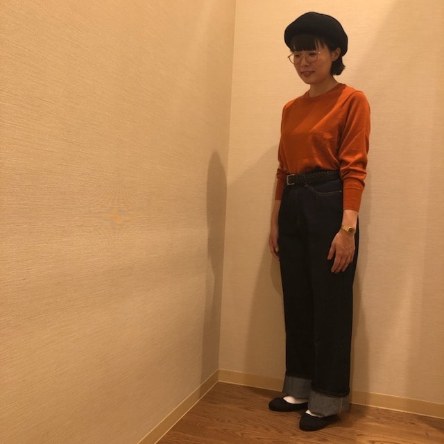 バギーデニムとレンガ色のクルーネックニセーターを着用した女性の写真